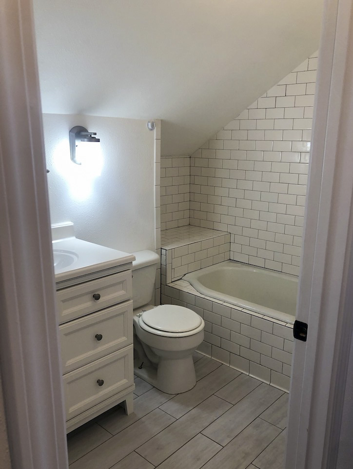 finished bathroom with tiled shower and angled ceiling